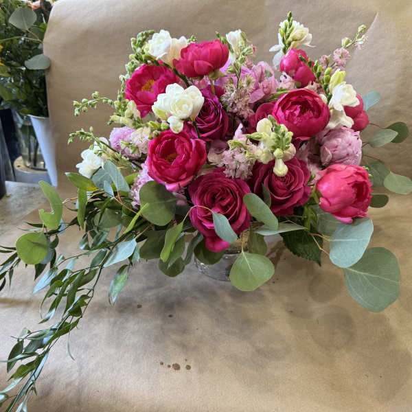 Pink and white bouquet in a clear vase with trailing greenery