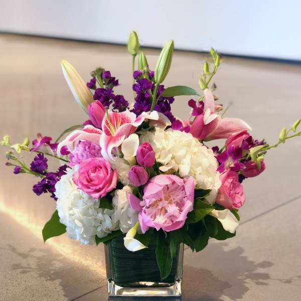 Pink and white floral arrangement in a square glass vase