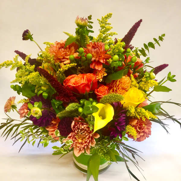 Bright mixed bouquet in a glass vase with orange, yellow, and purple flowers