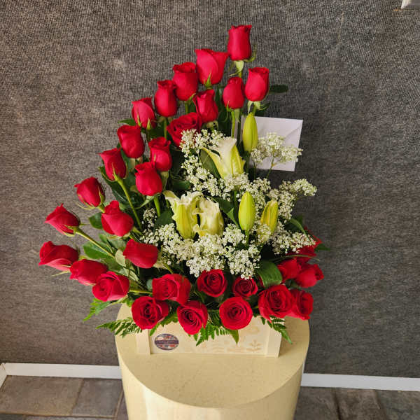Red roses and white lilies arranged in a cream box