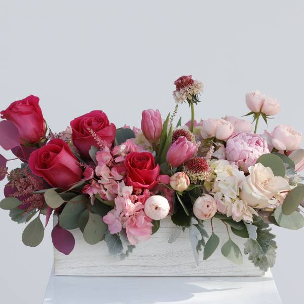 Pink and white floral arrangement in a white wooden box
