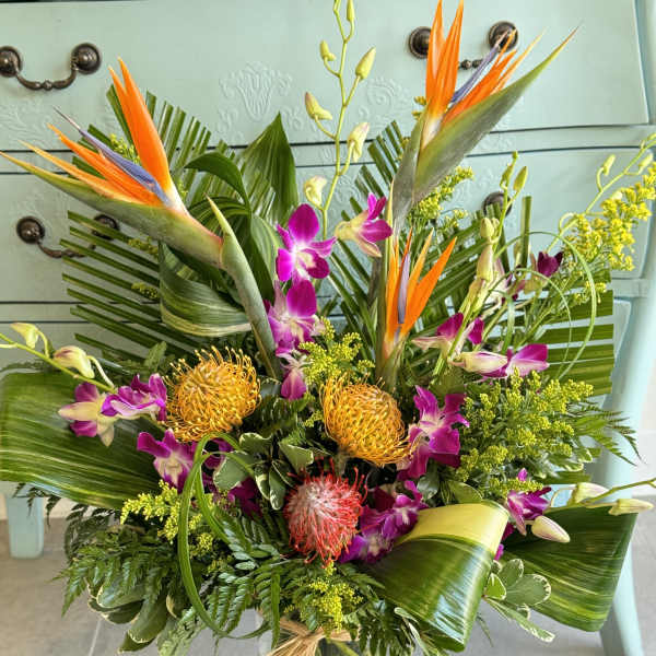 Tropical bouquet with orange bird-of-paradise and purple orchids in a glass vase