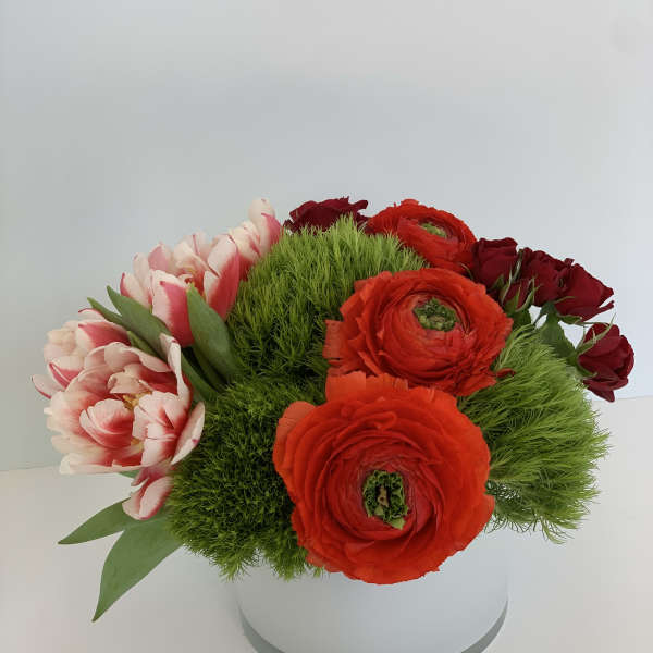 Round bouquet of red and pink flowers in a white box