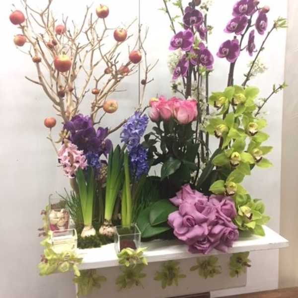 Tall floral display with orchids, tulips, hyacinths, and decorative branches