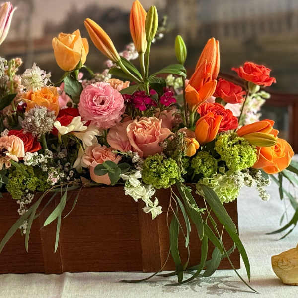 Rectangular wooden box filled with orange tulips, pink and peach roses, and mixed spring flowers