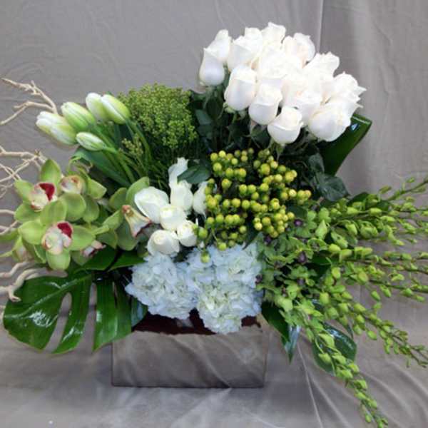 White floral arrangement with orchids and roses in a square vase