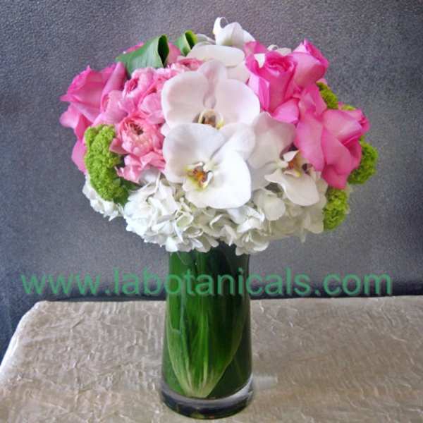 Pink and white bouquet in a tall green glass vase