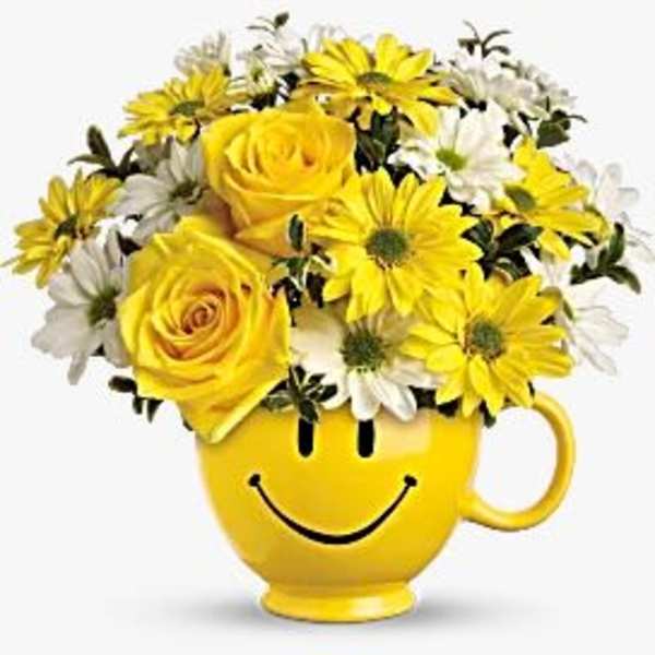 Yellow and white flowers arranged in a smiley-face mug
