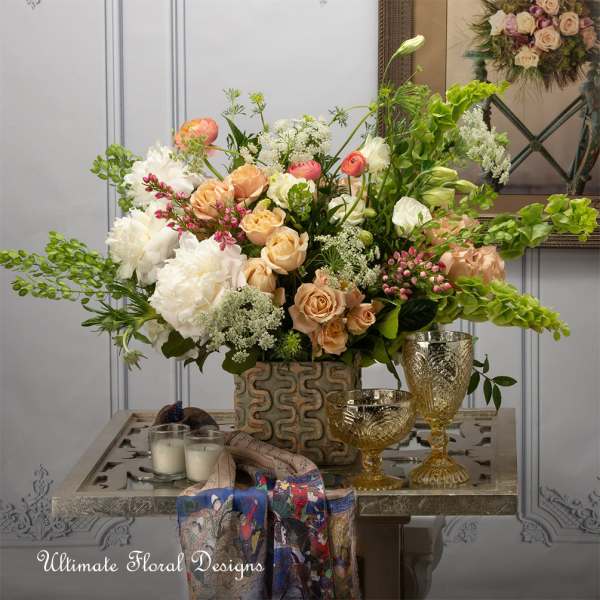 Large floral arrangement with peach and white roses in a decorative vase