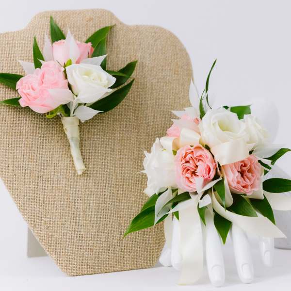 Pink and white rose corsage and boutonniere with ribbon on display