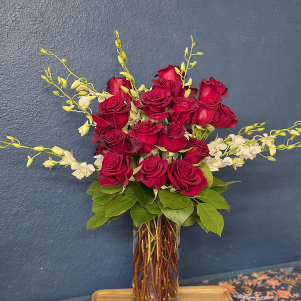 Red roses arranged in a clear glass vase with white accent flowers