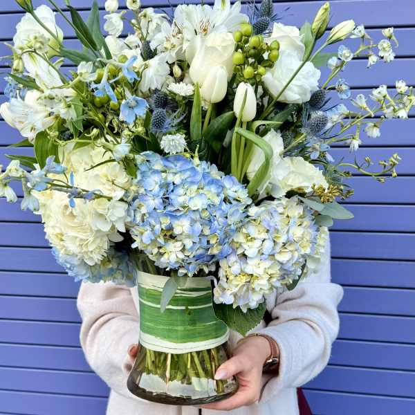 Large bouquet of white and blue flowers in a glass vase