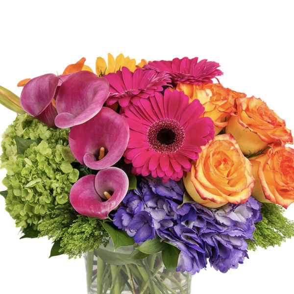 Colorful bouquet with roses, gerbera daisies, calla lilies, and hydrangeas in a glass vase