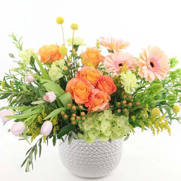Orange roses and pale pink daisies in a white textured vase