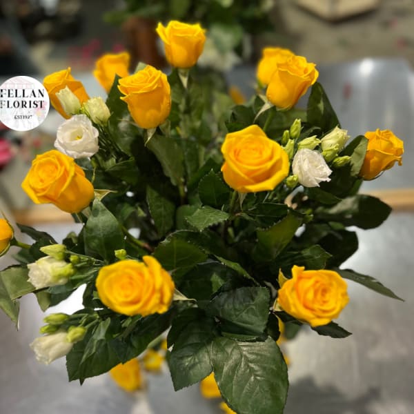 Arrangement of bright yellow roses with a few white blooms in a clustered bouquet