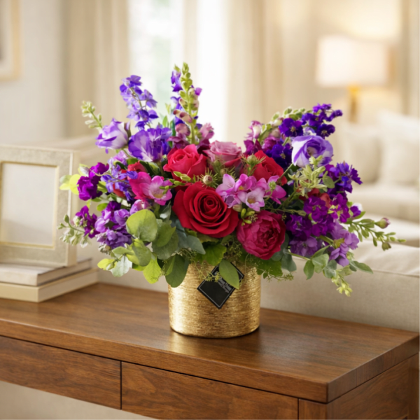 Bouquet of red roses and purple flowers in a gold vase