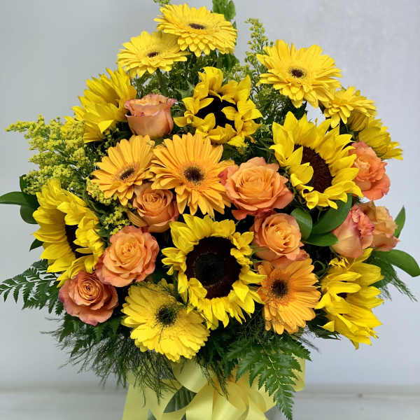 Bouquet of yellow sunflowers and peach roses in a glass vase