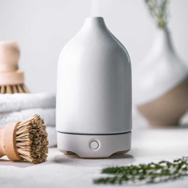 White ceramic essential oil diffuser emitting mist on a spa-like counter