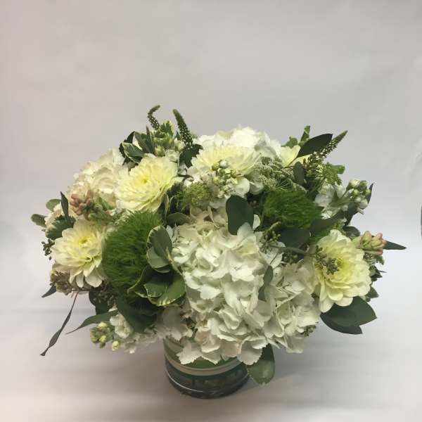 White and pale yellow floral arrangement in a round container