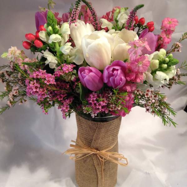 Bouquet of pink, white, and purple flowers in a burlap-wrapped vase