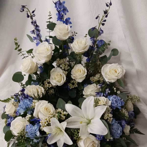 White roses and lilies with blue flowers in a low arrangement