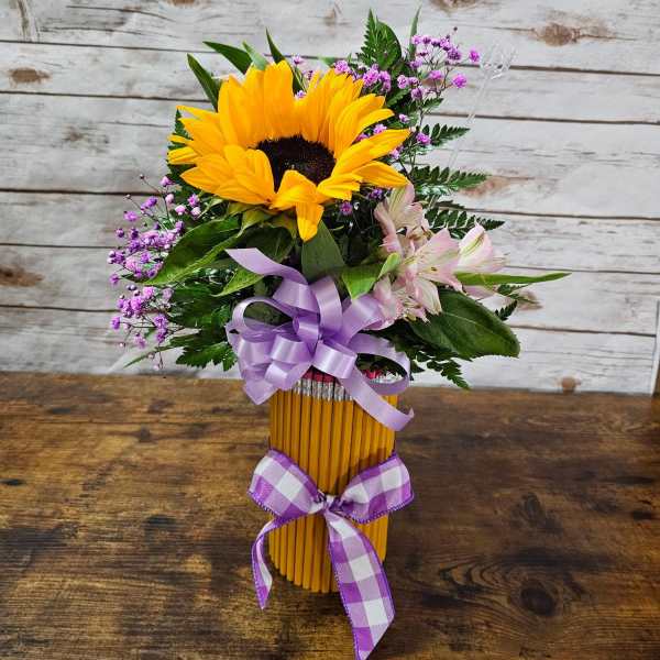 Sunflower bouquet in a pencil vase with purple ribbon and pink accent flowers