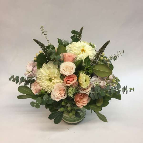 Mixed bouquet of pale pink and cream flowers in a glass vase