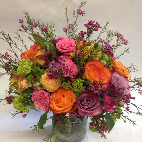 Mixed bouquet of roses and small purple flowers in a glass vase
