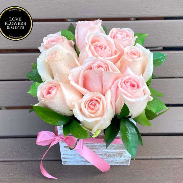 Blush pink roses with water droplets in a white wooden box tied with a pink ribbon