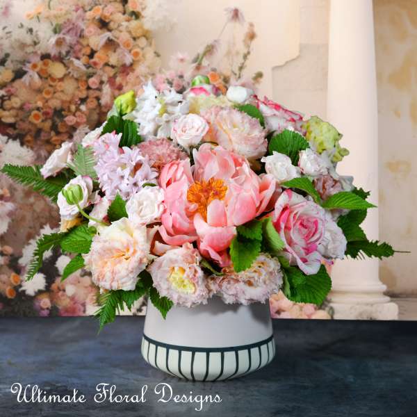 Pink and white floral arrangement in a striped ceramic vase