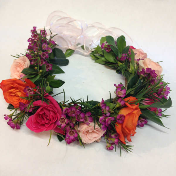 Floral wreath with pink, orange, and purple blooms on a white ribbon base
