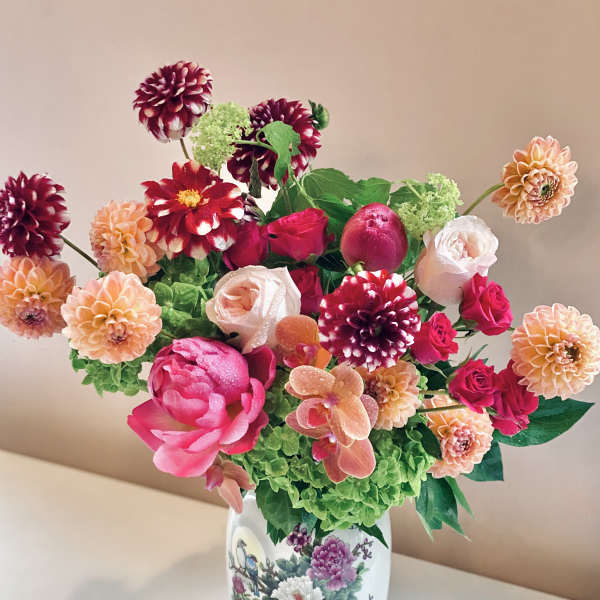 Colorful bouquet of dahlias, roses, and orchids in a decorative vase