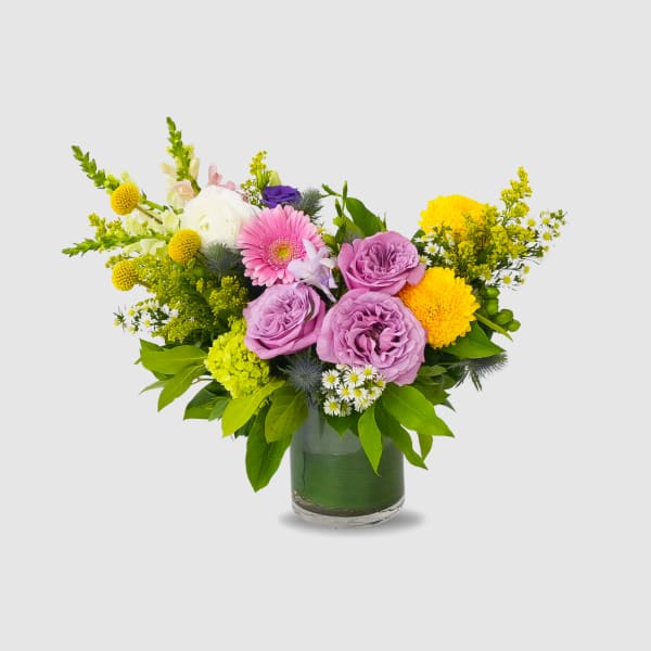 Mixed bouquet of pink and yellow flowers in a glass vase