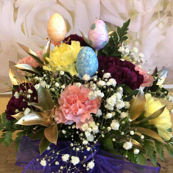 Colorful flower arrangement with glittered Easter eggs and purple ribbon