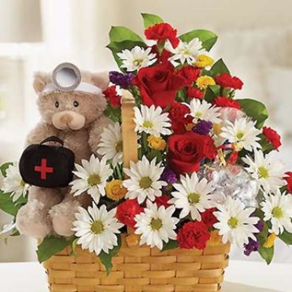 Basket arrangement with red roses, daisies, and a teddy bear holding a medical bag