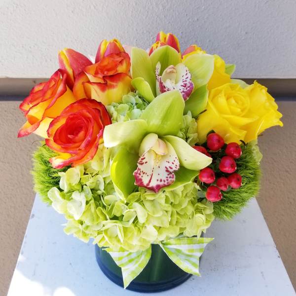 Bouquet of yellow and red roses with green orchids in a vase