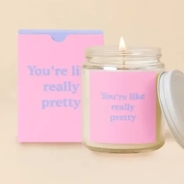 Lit candle in a glass jar with a pink label and matching box