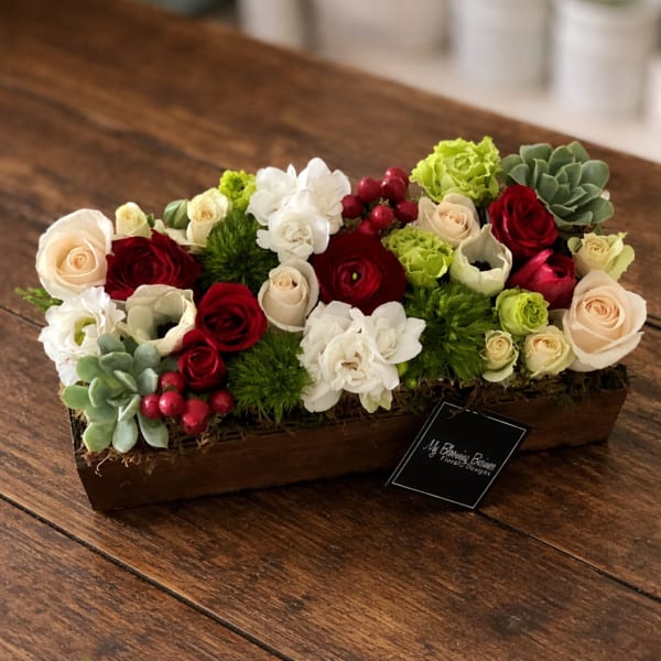 Low floral centerpiece with red, white, and blush roses in a wooden box