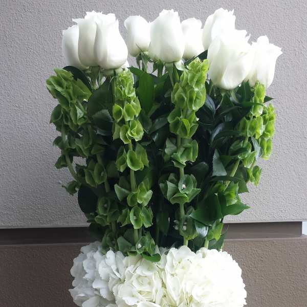 White roses and hydrangeas in a tall green vase
