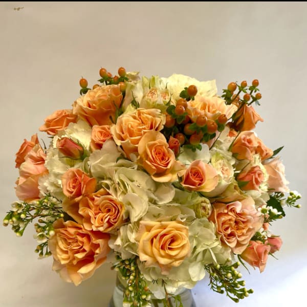 Peach roses and white hydrangeas in a clear glass vase