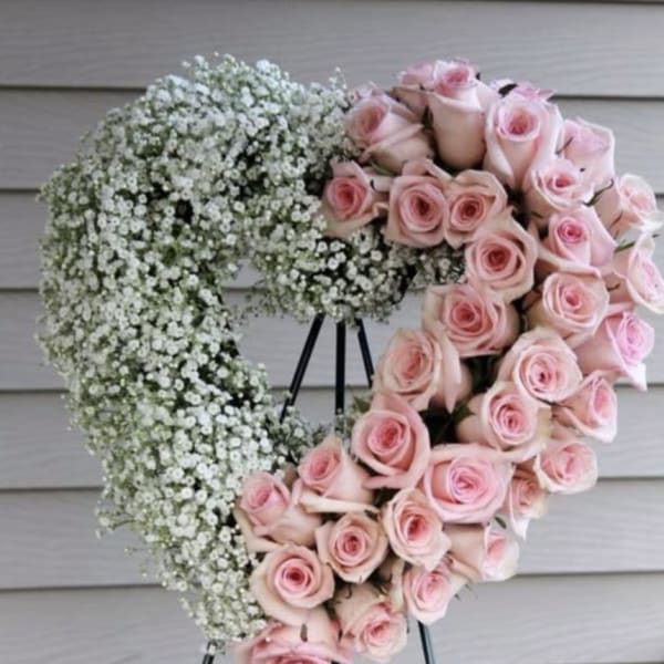 Heart-shaped wreath of pink roses and white baby's breath on a stand