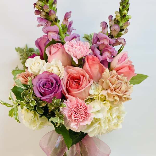 Pink and purple bouquet in a glass vase with a pink ribbon