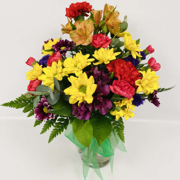 Colorful mixed bouquet in a clear glass vase with a green ribbon