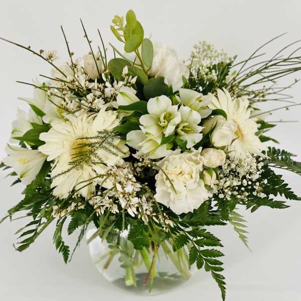 White floral bouquet in a clear glass vase with mixed greenery