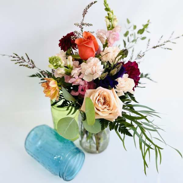 Mixed bouquet of roses, carnations, and snapdragons in a glass vase