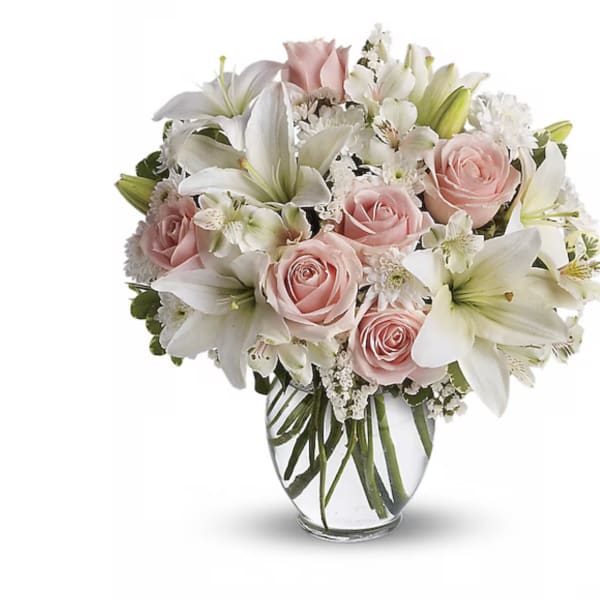 Pink roses and white lilies arranged in a clear glass vase