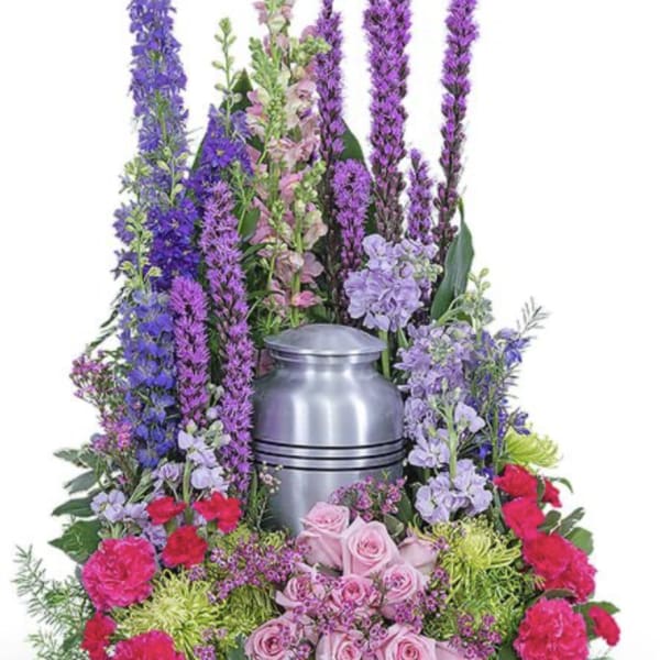 Purple and pink floral arrangement around a silver urn