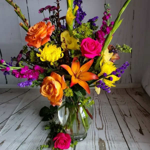 Colorful mixed bouquet in a clear glass vase with roses and lilies