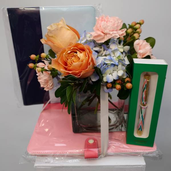 Bouquet of peach roses, blue hydrangea, and pink carnations with gift items