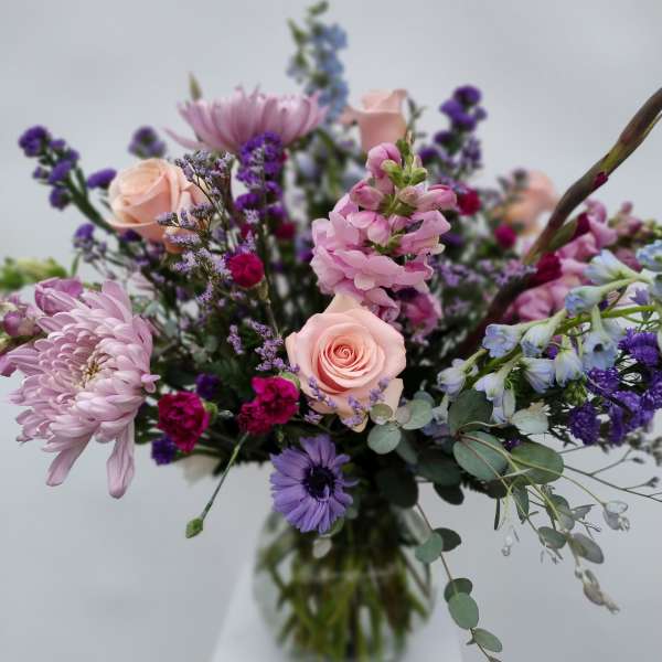 Mixed bouquet of pink and purple flowers in a glass vase